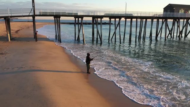 Man fishing at sunrise at Belmar beach, New Jersey.