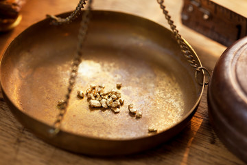 Weighing a gold nugget on a old brass scale dish for trade or exchange.