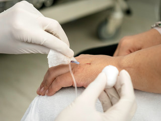 Nurse hands using medical and pull  IV Catheter on patient hand for remove the saline needle in the hospital room