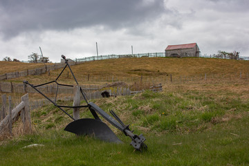Primer plano de arado manual con vista de casa en la colina.