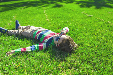 The boy is lying on the grass.