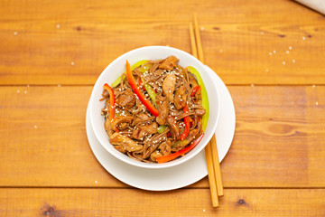 Noodles with pork, vegetables and sesame. On a wooden table.