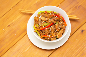 Noodles with pork, vegetables and sesame. On a wooden table.