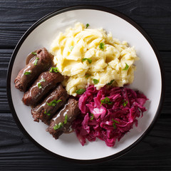 Beef rolls with mustard, bacon and pickles served with mashed potatoes and red cabbage close-up....