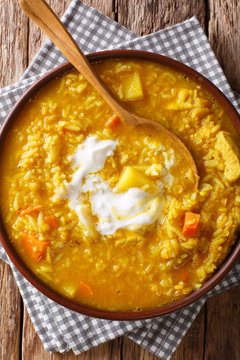 Delicious thick Mulligatawny soup of red lentils, rice and spices close-up in a bowl. Vertical top view