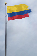 Fototapeta na wymiar Worn and tattered Colombia flag blowing in the wind on a cloudy day