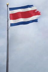 Worn and tattered Costa Rica flag blowing in the wind on a cloudy day