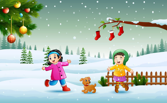 Happy kids wearing a winter chlotes playing on the snow in christmas day