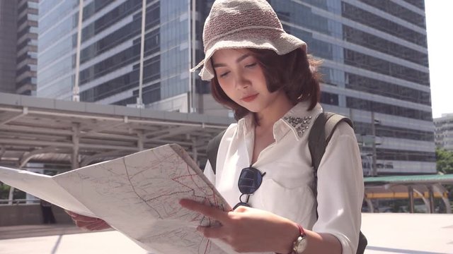 Slow motion - Cheerful beautiful young Asian backpacker woman direction and looking on location map while traveling at Bangkok, Thailand. Lifestyle backpack tourist travel holiday concept.