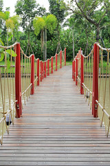 Wooden rope suspension bridge for walk crossing river.