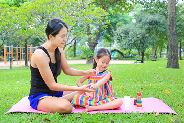 Mother appying body lotion for daughter's in the summer park.