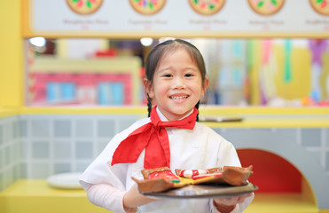 Kid girl in a suit of the little chef make pizza, Cooking child concept.