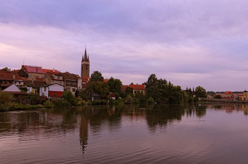 Fototapeta na wymiar Morning cityscape of medieval Telc. Tower of Church of the Holy Spirit in Telc reflected in the water of the castle lake. A UNESCO World Heritage Site