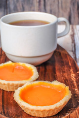 Egg tart and a cup of coffee on wooden background