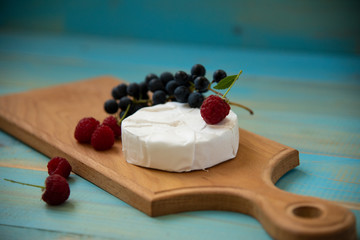 cheese camembert with raspberries and grapes on a table