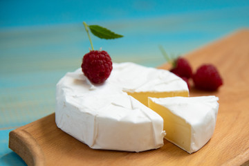 cheese camembert with raspberries on a blue table