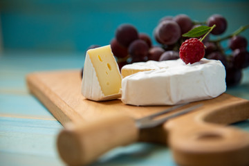 cheese camembert with raspberries and grapes on table