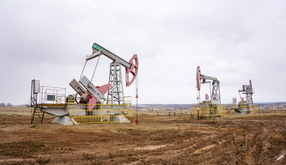 The oil pump, industrial equipment. Oil field site, oil pumps are running. Rocking machines for oil production