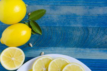 bright yellow lemons and lemon slices on a blue background