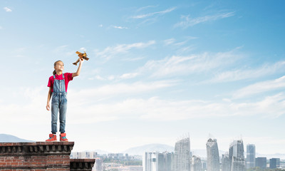 Concept of careless happy childhood with girl dreaming to become pilot