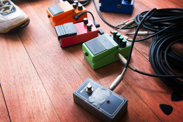 Electric guitar audio processing effects  on a studio floor. Stomp box type effectors and cables on...