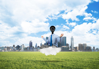 Camera headed man sitting in lotus pose on cloud against modern cityscape