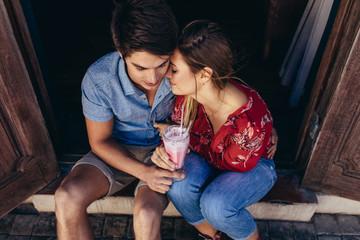 Romantic tourist couple sitting at the doorstep with a milkshake