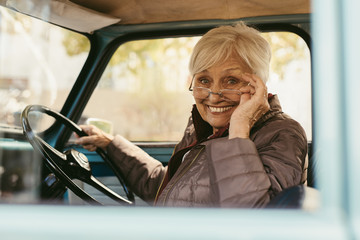 Elder woman driving a old car