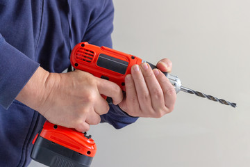 Man holding an orange electric drill on batteries