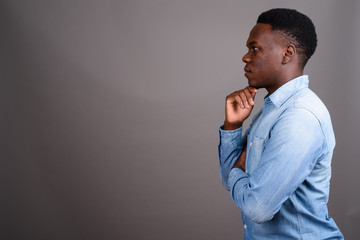 Young African man wearing denim shirt against gray background