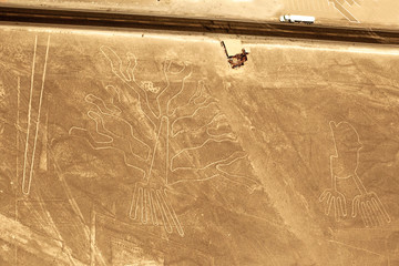A large truck on the highway driving past the Nazca Lines glyphs known as the Cactus and the hands,...