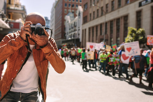 Man shooting pictures of rally on road