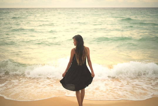 Young asian Vietnamese woman standing on beach posing with black dress and sea in background