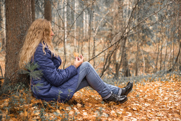 girl sitting near a tree in the autumn forest