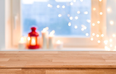 Wooden tabletop over blurred christmas lights on frosted window background