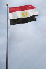 Worn and tattered Egypt flag blowing in the wind on a cloudy day