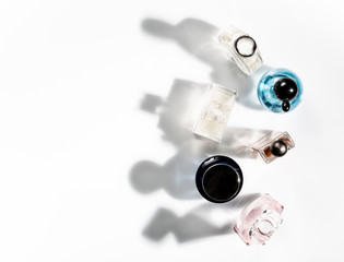 Shadows of perfume bottles falling on a white background. View from above.
