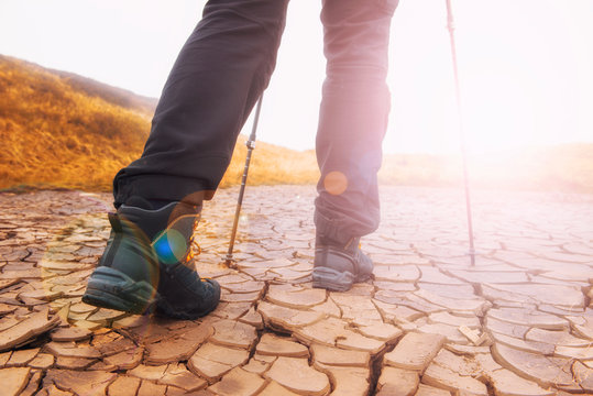 Closeup image of hiker legs in a touristic boots wallking forward on the dry cracked ground