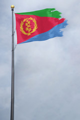 Worn and tattered Eritrea flag blowing in the wind on a cloudy day