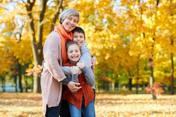 Fototapeta premium Happy family walks in autumn city park. Children and parents posing, smiling, playing and having fun. Bright yellow trees.