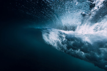 Barrel wave underwater with air bubbles and sun light.