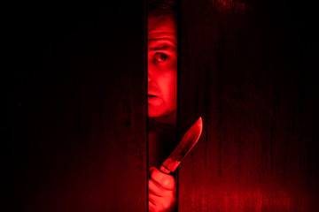 Serial killer / eye peeking behind the door with kinfe