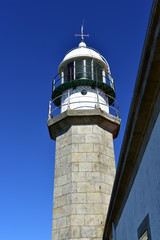 Fototapeta na wymiar Old white lighthouse with wind vane. Blue sky, Galicia, Spain.