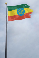 Worn and tattered Ethiopia flag blowing in the wind on a cloudy day