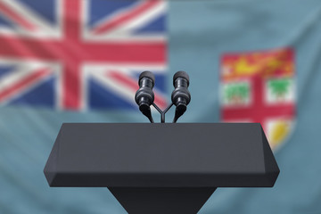 Podium lectern with two microphones and Fiji flag in background