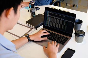 A male programer working with laptop and coding on computer.