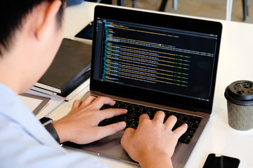 A male programer working with laptop and coding on computer.