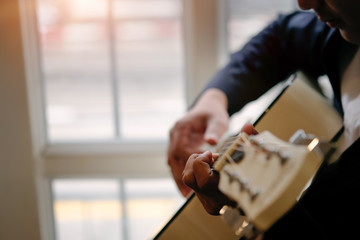 Closeup man playing an acoustic guitar with vintage tone.
