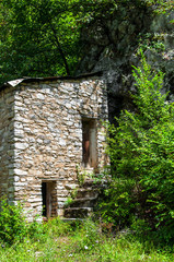 Fototapeta na wymiar an old stone building standing by a rock in the middle of a forest