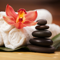 Spa background. White towels on exotic plant, beautiful orchid flower and balancing stones for...